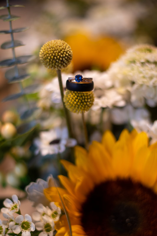 A picture of a blue sapphire engagement ring on sunflower wedding florals. 